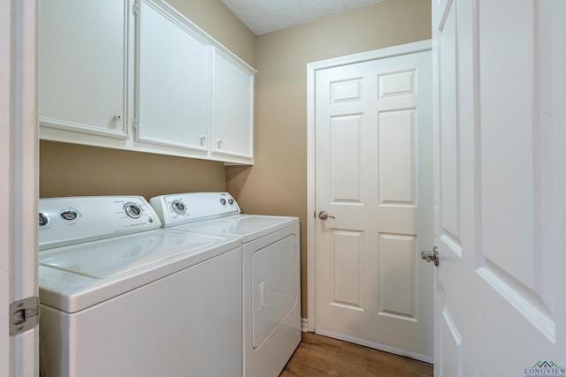 laundry area with light wood-type flooring, cabinet space, and washing machine and dryer