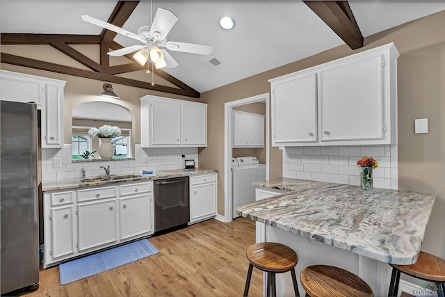 kitchen featuring a breakfast bar, white cabinets, a sink, independent washer and dryer, and stainless steel appliances