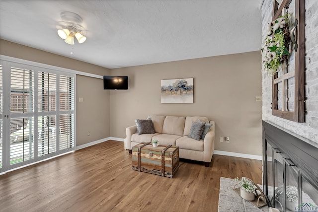 living room with baseboards, ceiling fan, and wood finished floors