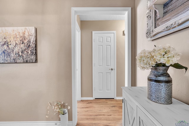 hall with light wood-style floors and baseboards