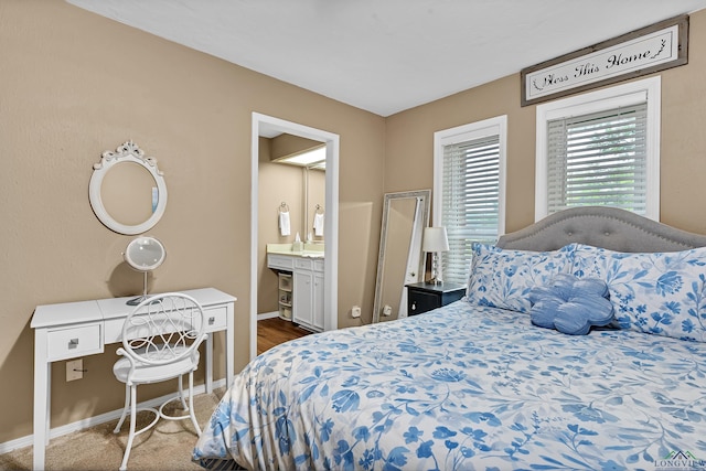 carpeted bedroom featuring baseboards and connected bathroom