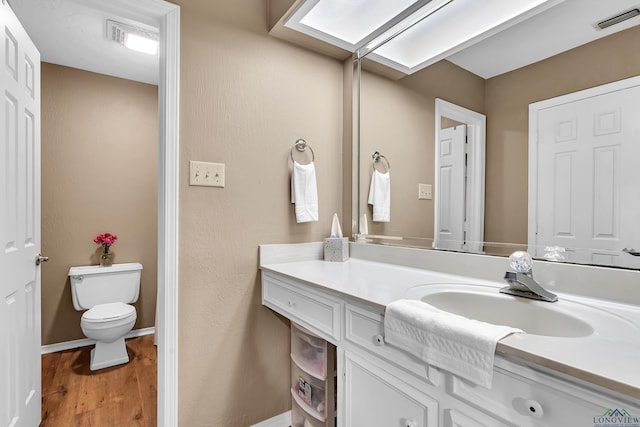 bathroom featuring visible vents, wood finished floors, toilet, and vanity
