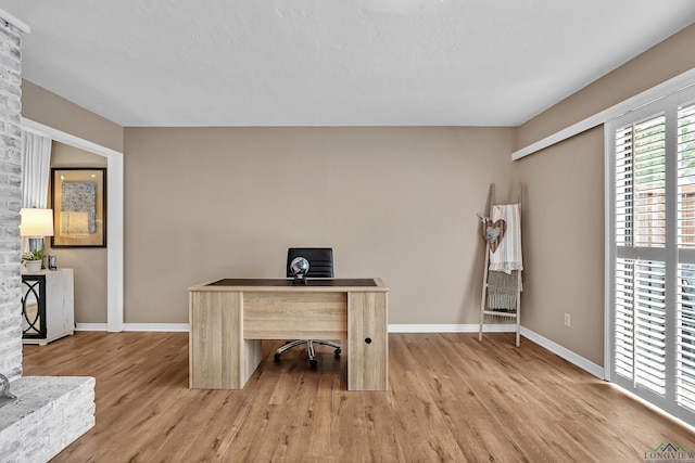 unfurnished office featuring baseboards and light wood-style flooring