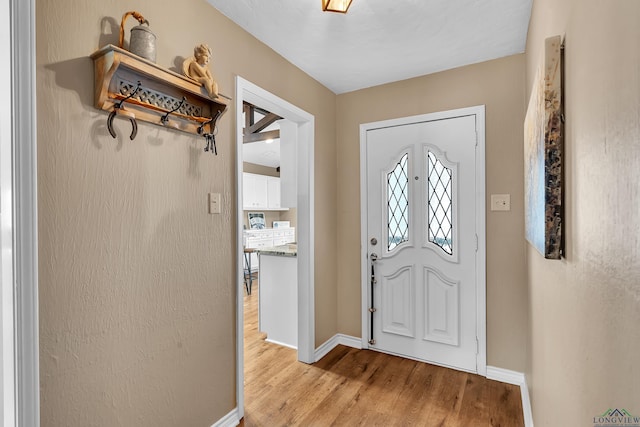 foyer entrance featuring baseboards and light wood-type flooring