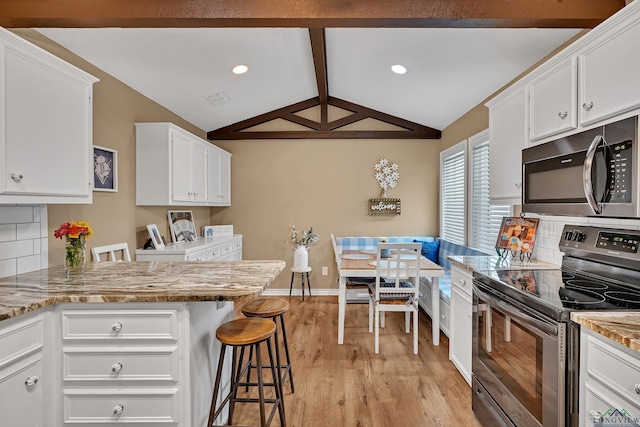 kitchen with white cabinets, light wood-style flooring, stainless steel appliances, vaulted ceiling with beams, and backsplash