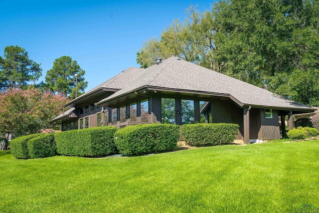 rear view of house featuring a yard and a shingled roof