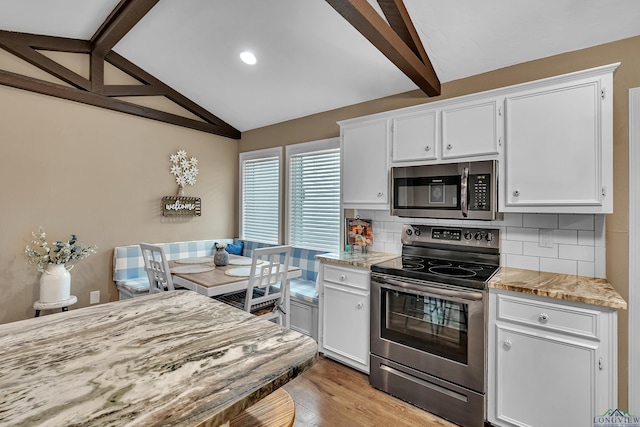 kitchen with white cabinets, appliances with stainless steel finishes, lofted ceiling with beams, and tasteful backsplash