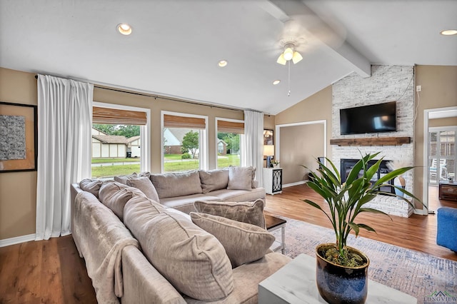 living room with ceiling fan, a fireplace, wood finished floors, baseboards, and lofted ceiling with beams