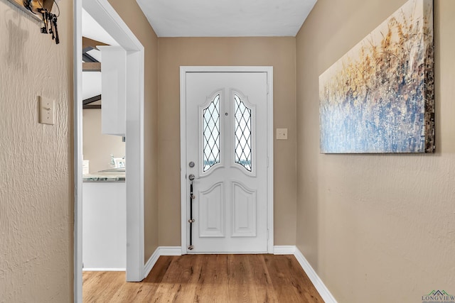 foyer entrance featuring baseboards and wood finished floors