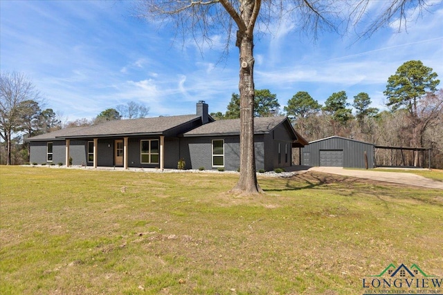 view of front of house with a chimney, a front yard, a garage, driveway, and an outdoor structure