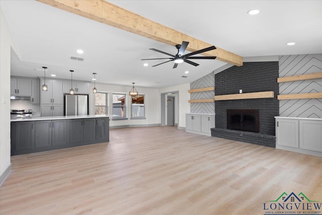 unfurnished living room with light wood finished floors, visible vents, ceiling fan, vaulted ceiling with beams, and a fireplace