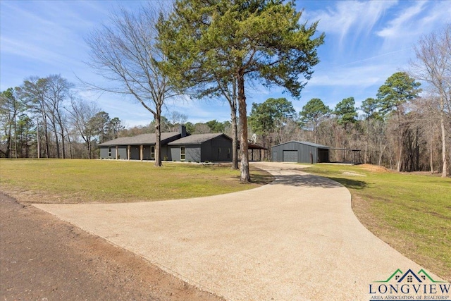 view of front facade with an outbuilding, a detached garage, an outdoor structure, concrete driveway, and a front yard