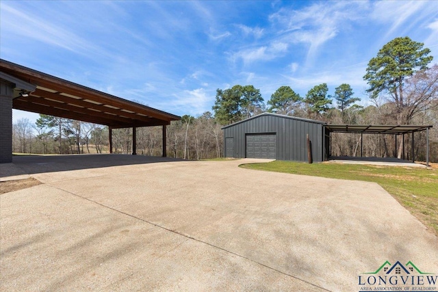 view of patio / terrace featuring driveway, a detached garage, and an outbuilding