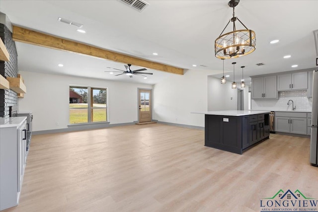 kitchen featuring gray cabinetry, a sink, visible vents, light countertops, and beam ceiling