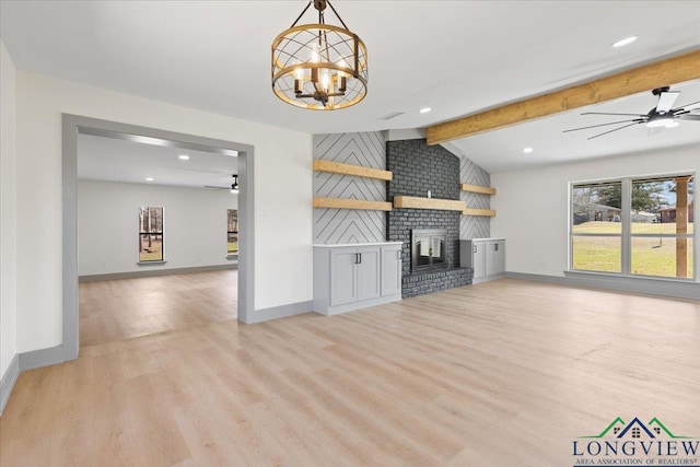 unfurnished living room with lofted ceiling with beams, ceiling fan with notable chandelier, light wood-style flooring, and a brick fireplace