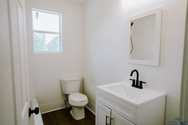 bathroom with baseboards, wood finished floors, vanity, and toilet