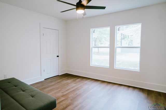 living area with wood finished floors, baseboards, and ceiling fan