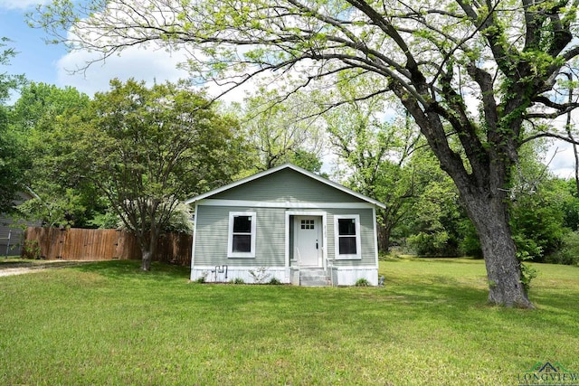 bungalow-style home featuring a front lawn and fence