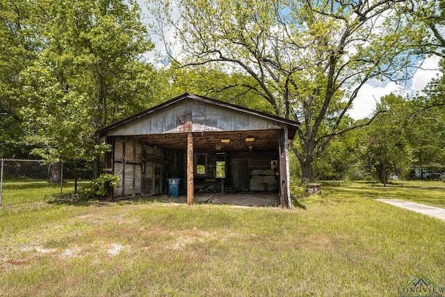 view of pole building with fence, a lawn, and a detached carport