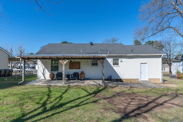 back of house featuring a patio, a lawn, and roof with shingles