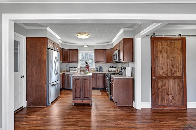 kitchen featuring a barn door, stainless steel appliances, a kitchen island, ornamental molding, and dark wood-style floors