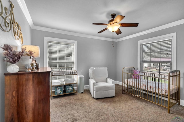 carpeted bedroom with baseboards, ceiling fan, a crib, and crown molding