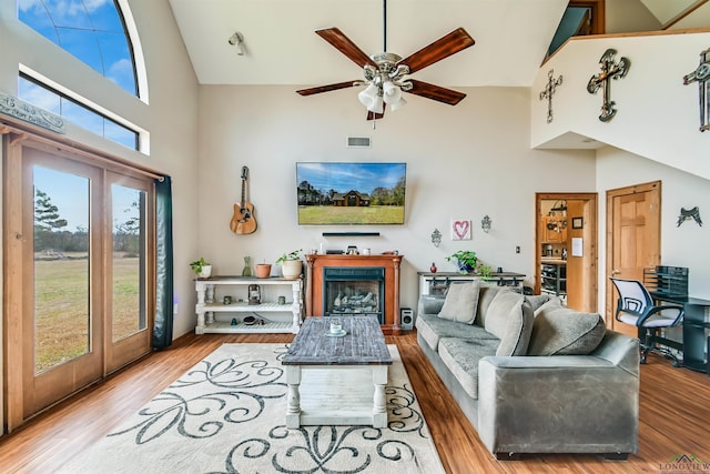 living room featuring high vaulted ceiling, a fireplace, wood finished floors, visible vents, and french doors