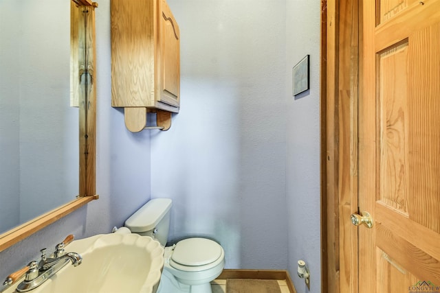 bathroom with baseboards, a sink, and toilet