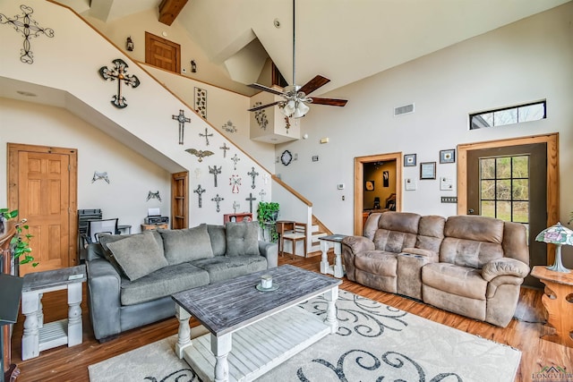 living room featuring visible vents, a ceiling fan, stairway, wood finished floors, and beamed ceiling