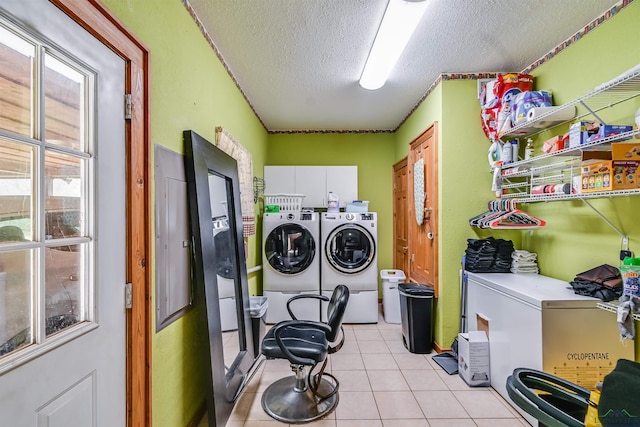 laundry area featuring light tile patterned floors, a textured ceiling, washing machine and dryer, and cabinet space