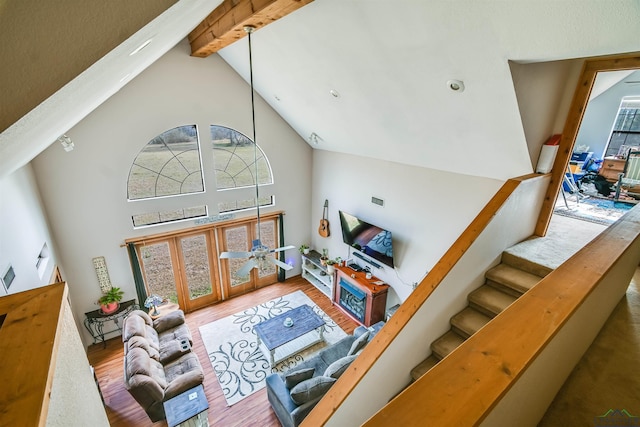 living area with stairs, high vaulted ceiling, beamed ceiling, and wood finished floors