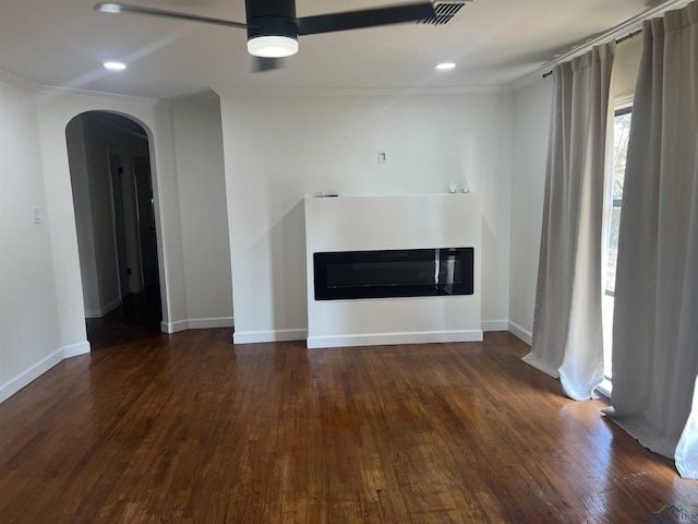 unfurnished living room featuring ceiling fan, dark hardwood / wood-style flooring, and ornamental molding