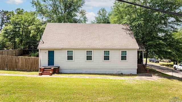 exterior space featuring roof with shingles, fence, and a yard