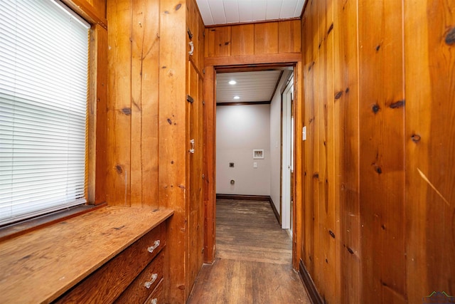 hallway with dark wood finished floors, wood walls, and baseboards