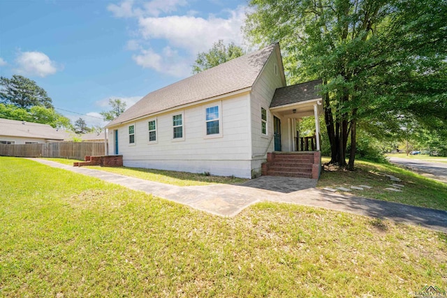 view of front of property with fence, a shingled roof, and a front yard