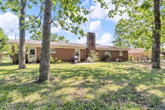 back of property featuring a lawn, a patio, fence, a chimney, and central AC unit