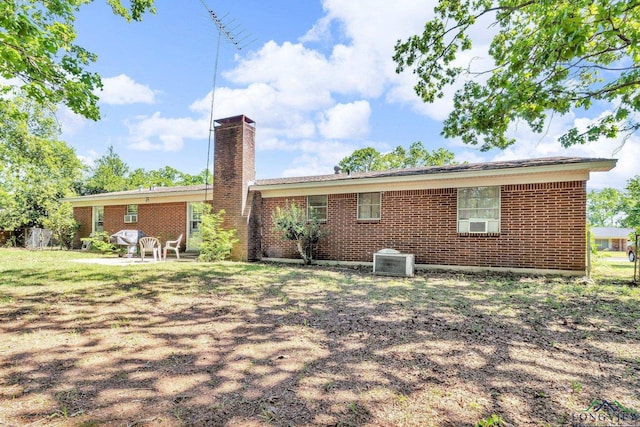rear view of house featuring brick siding, central AC unit, and a chimney