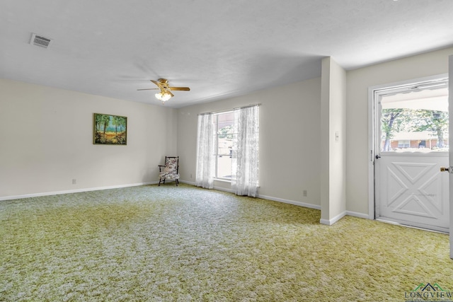 carpeted empty room with visible vents, baseboards, and a ceiling fan