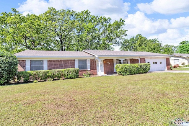 single story home featuring brick siding, a front lawn, an attached garage, and driveway