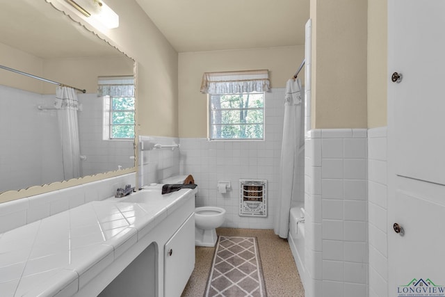 bathroom with vanity, toilet, heating unit, wainscoting, and tile walls