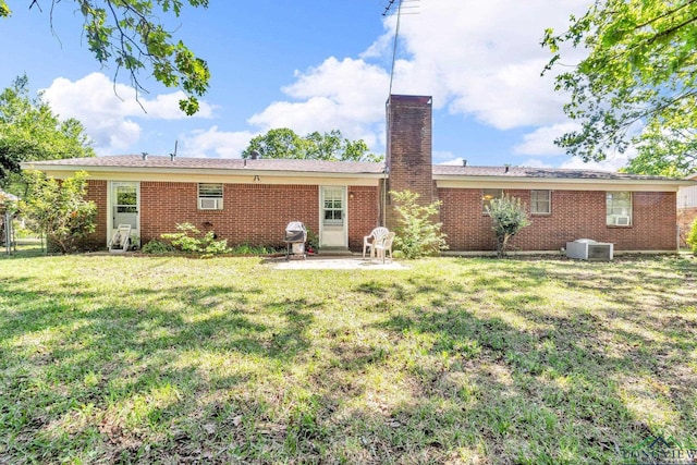 back of property featuring a lawn, a chimney, a patio, central air condition unit, and brick siding