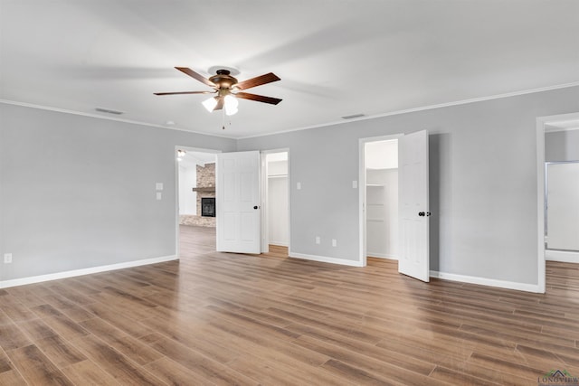 unfurnished bedroom with a brick fireplace, crown molding, and wood finished floors