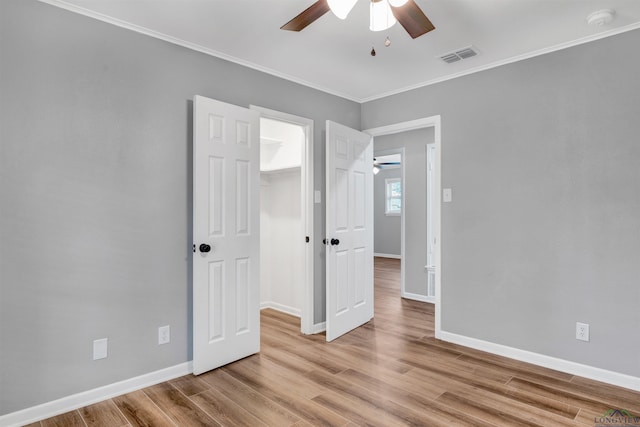 unfurnished room with baseboards, visible vents, ceiling fan, ornamental molding, and wood finished floors