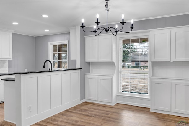 kitchen with tasteful backsplash, white cabinets, crown molding, and light wood-style flooring