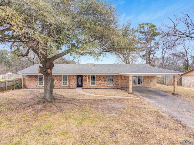 ranch-style house featuring a carport, driveway, brick siding, and fence