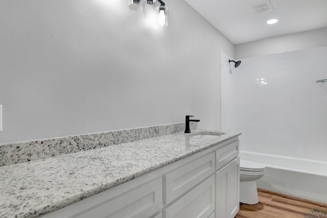 bathroom with toilet, shower / bath combination, wood finished floors, vanity, and visible vents