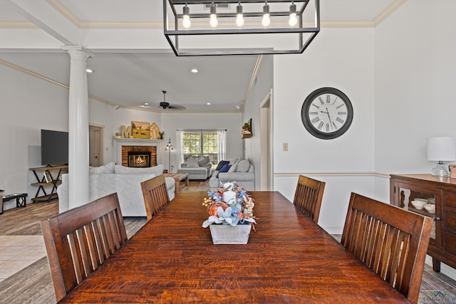 dining room with tile patterned flooring, decorative columns, a brick fireplace, and ceiling fan