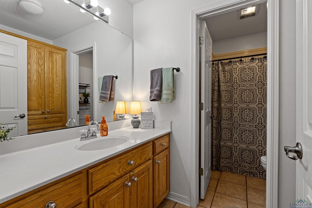 bathroom featuring tile patterned flooring, vanity, toilet, and walk in shower