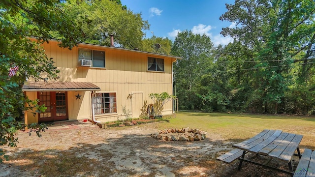 rear view of property featuring a fire pit, french doors, cooling unit, and a yard