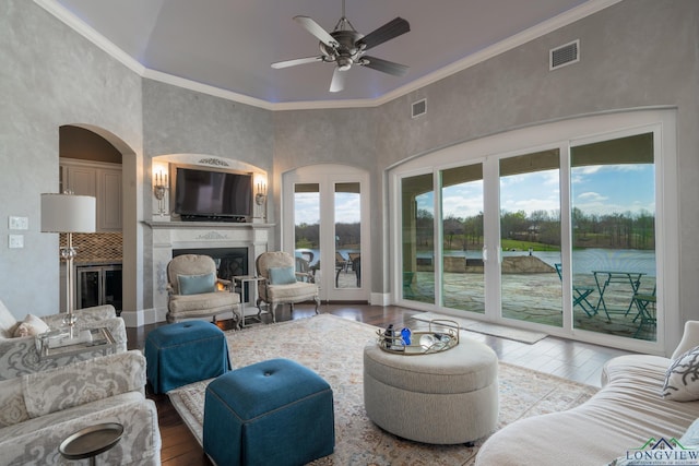 living room with a large fireplace, hardwood / wood-style flooring, ceiling fan, and crown molding